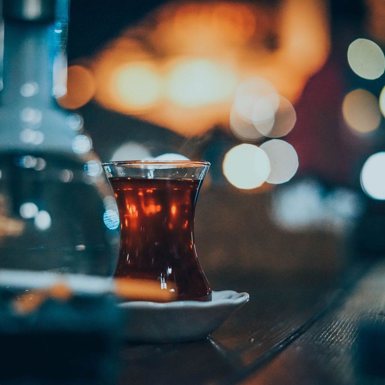 A glass of black tea poured from a samovar, served with saffron rock sugar